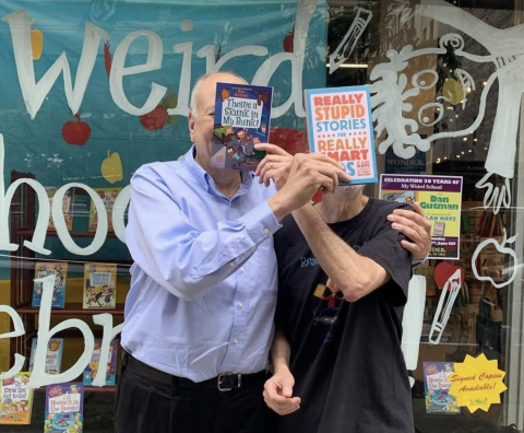 Dan Gutman and Alan Katz holding books in front of there faces