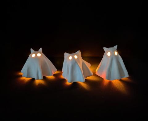 3 cat ghosts made out of air dry clay, they are glowing because of a tea light under each one