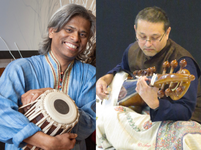 Man at left smiling and holding tabla instrument and man at right looking down while playing sarod instrument