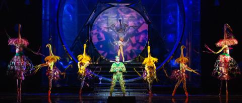 People in colorful costumes spotlighted on a dark stage 