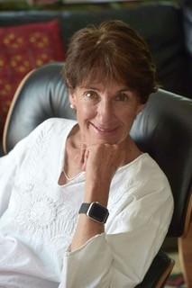 White woman with short brown hair leaning chin on left hand