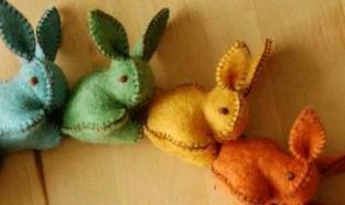 Small felt bunnies in blue, green, yellow, and orange. 