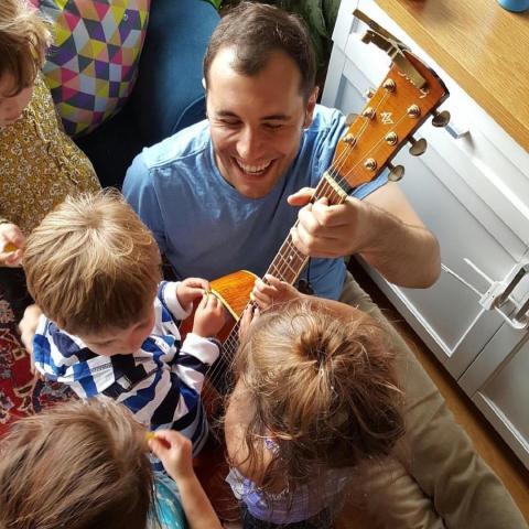 Man with Guitar surronded by kids