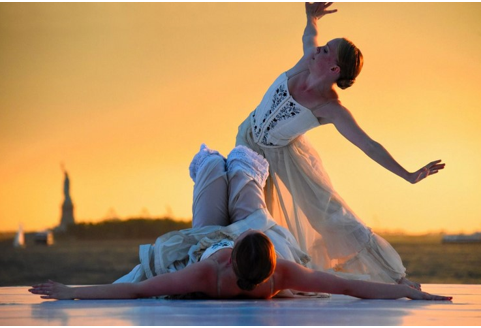 Two dancers outside with statue of liberty in background