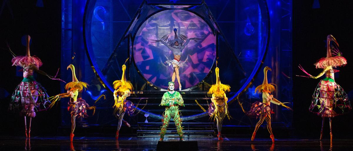 People in colorful costumes spotlighted on a dark stage 