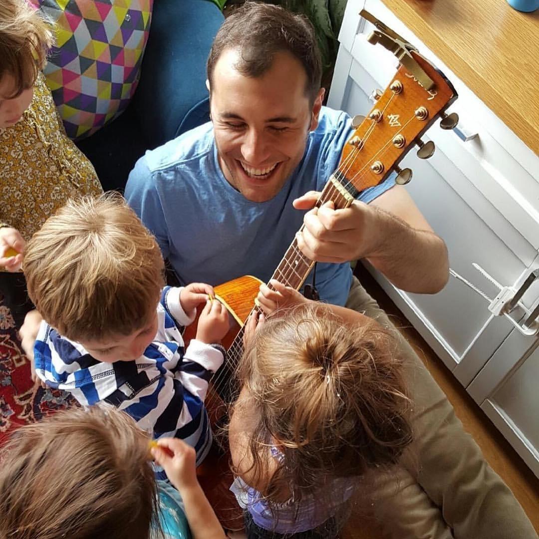 Man with Guitar surronded by kids