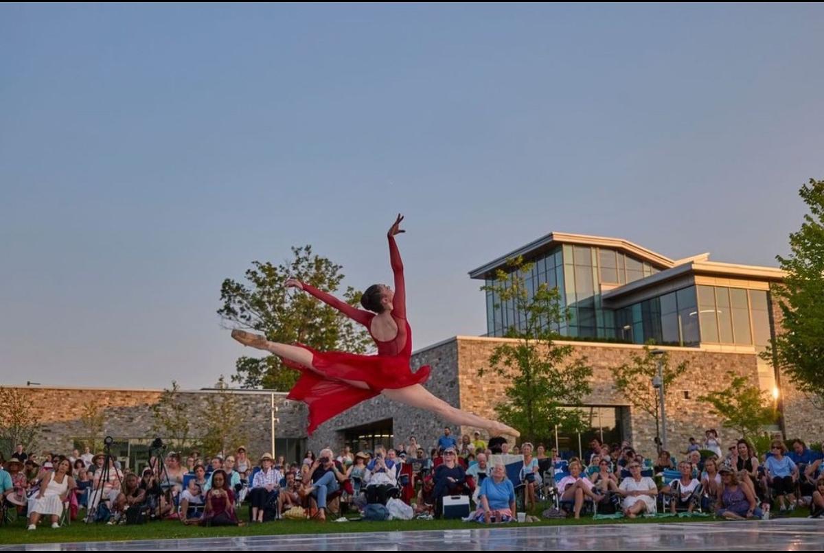 A dancer jumping in front of library building 